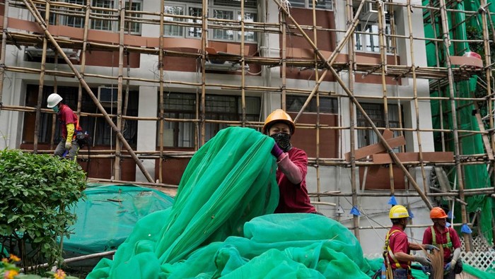 Workers remove scaffolding mesh from a building at Sui Wo Court in Sha Tin, following authorities' decision to remove the netting amid investigations into a deadly fire at Wang Fuk Court, in Hong Kong, China December 4, 2025. REUTERS/Vernon Yuen     TPX IMAGES OF THE DAY