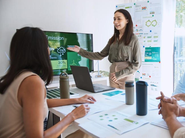 Asian woman lead young group of multiethnic businesspeople in team meeting, using laptop computer for ESG topic presentation on monitor. Sustainable business practice, people work at home concept