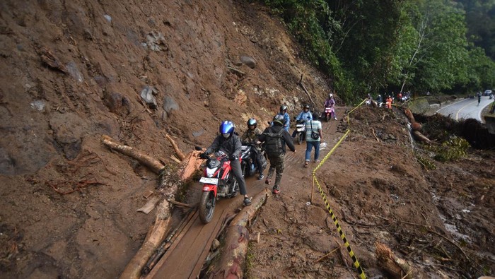 Pengendara melintasi jalan darurat di kawasan Mega Mendung, Lembah Anai, Tanah Datar, Sumatera Barat, Kamis (4/12/2025). Jalan darurat tersebut dibangun oleh swadaya masyarakat akibat putusnya akses jalan nasional Padang - Bukittinggi karena banjir bandang, sementara hanya bisa dilewati pengendara motor dan pejalan kaki diluar jam kerja pekerjaan rehablitasi jalan. ANTARA FOTO/Iggoy el Fitra/nz