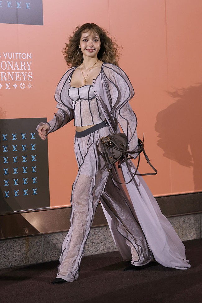 Untuk busana, rapper asal Thailand ini set berbahan sheer yang ringan dengan aksen garis hitam kontras. Bustier dan celana longgar senada memberi efek struktural meski materialnya tipis. Foto: WireImage/Han Myung-Gu