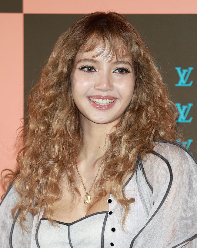 Rambut blonde-nya ditata keriting bervolume dengan soft bangs yang membingkai wajah, menghasilkan tampilan playful sekaligus girlie. Sementara itu, riasan wajah dibuat lembut dan glowing dengan bulu mata panjang nan lentik. Bibir diberi sentuhan lip gloss yang memberi kesan segar. Foto: ImaZins via Getty Images/The Chosunilbo JNS