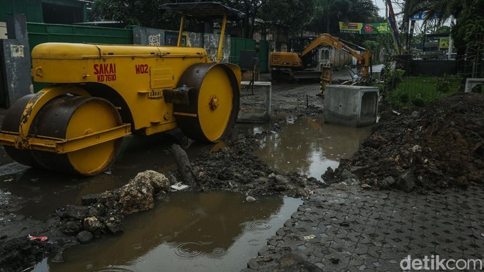 Petugas menggunakan alat berat mengerjakan proyek jalan dan drainase di Jalan PU, Cimuning, Kota Bekasi, Kamis (4/12/2025).