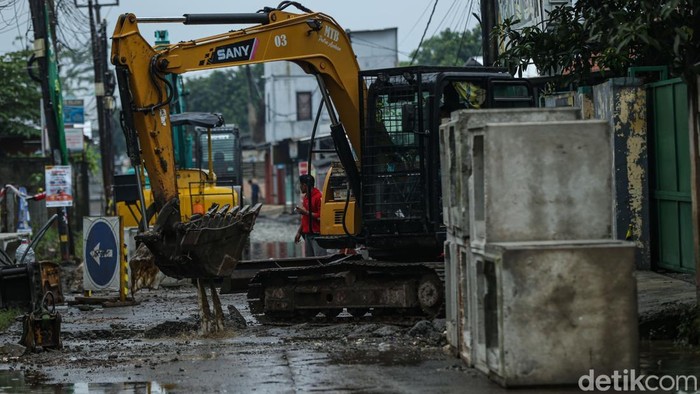 Petugas menggunakan alat berat mengerjakan proyek jalan dan drainase di Jalan PU, Cimuning, Kota Bekasi, Kamis (4/12/2025).
