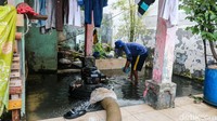 Petugas membantu membersihkan sisa air yang masih menggenangi bagian dalam rumah usai banjir rob di Kampung Marunda Pitung, Jakarta Utara, pada Kamis siang (4/12/2025).