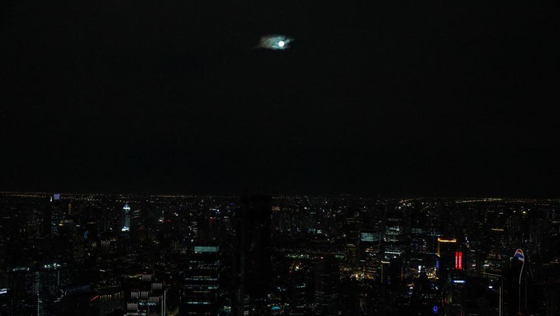Supermoon terakhir tahun 2025, yang dikenal sebagai Cold Moon atau Bulan Dingin, menghiasi langit Bangkok pada Kamis (4/12) malam. Meski kota tersebut diselimuti awan tebal sejak sore hari, pesona bulan penuh berukuran besar itu tetap berhasil memecah langit yang muram dan memukau warga yang sempat menengadah. REUTERS/Athit Perawongmetha
