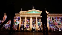 Seorang perempuan memotret proyeksi cahaya Natal musim dingin yang menerangi gedung GPO di Dublin, Irlandia, Rabu (3/12/2025). REUTERS/Clodagh Kilcoyne