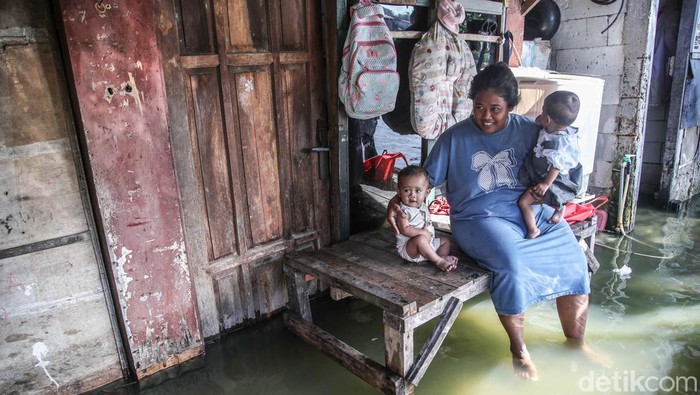Sejumlah warga beraktivitas di banjif rob kawasan Bambu Kuning, Marunda, Jakarta Utara, Jumat (5/12/2025). Air pasang laut yang mulai naik sejak Kamis malam kembali mencapai puncaknya pada pagi ini, menyebabkan permukaan air meluber ke permukiman dan akses jalan utama di wilayah tersebut.