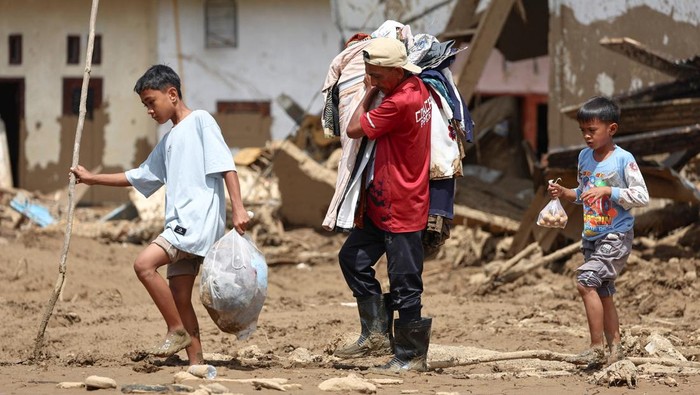Korban selamat Ilyasak Imam Mudo, 53 tahun, bersama anak-anaknya, mengumpulkan barang-barang berharga dari rumah mereka yang rusak berat akibat banjir bandang yang mematikan di Palembayan, Kabupaten Agam, Provinsi Sumatera Barat, Indonesia, 4 Desember 2025. REUTERS/Willy Kurniawan