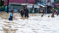 Warga melintasi genangan banjir yang merendam Jalan Raya Dayeuhkolot, Kabupaten Bandung, Jumat (5/12/2025). ANTARA FOTO/Novrian Arbi
