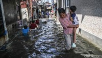 Sejumlah warga tampak terus beraktivitas di tengah genangan banjir rob yang merendam kawasan Kampung Empang, Muara Angke, Jakarta Utara, Jumat (5/12/2025).