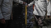 Petugas dengan menggunakan alat ukur, mengukur ketinggian rob di kawasan Muara Angke. Dengan kondisi rob yang masih berlangsung, aktivitas warga Muara Angke tetap berjalan hati-hati sembari menunggu air perlahan surut.