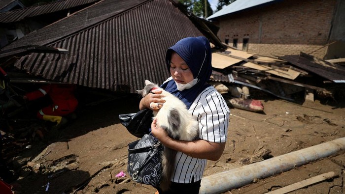 Survivor Ratnawita, 46, holds her cat named Embul after it was rescued from the rubble of her house, following a deadly flash flood in Palembayan, Agam regency, West Sumatra province, Indonesia, December 4, 2025. REUTERS/Willy Kurniawan