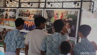 Pengunjung tampak antusias, berhenti di setiap panel untuk membaca keterangan foto dan mengabadikan suasana pameran.