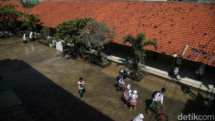 Sejumlah murid pulang sekolah saat banjir rob di kawasan MI EL Nur Kasysyaf, Kampung Bidara, Marunda, Jakarta Utara, Jumat (5/12/2025). Banjir rob yang mulai terjadi sejak kemarin ini mencapai puncaknya hari ini, dipicu oleh air pasang laut yang terus meningkat.