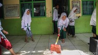Sejumlah murid tampak bahu - membahu membersihkan ruang kelas mereka dengan menggunakan alat seadanya.