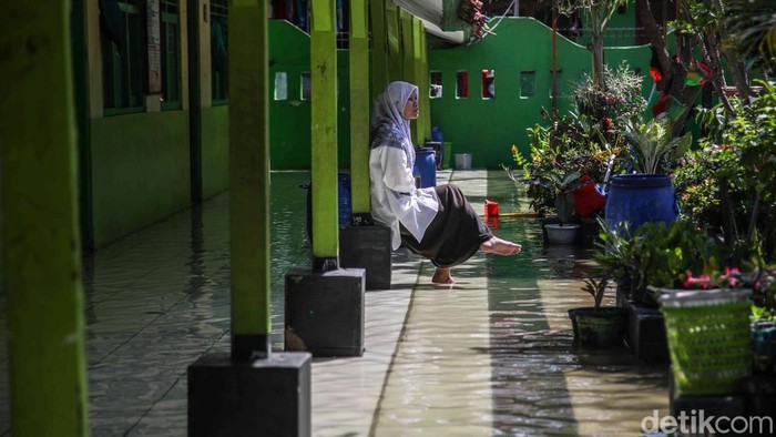 Sejumlah murid pulang sekolah saat banjir rob di kawasan MI EL Nur Kasysyaf, Kampung Bidara, Marunda, Jakarta Utara, Jumat (5/12/2025). Banjir rob yang mulai terjadi sejak kemarin ini mencapai puncaknya hari ini, dipicu oleh air pasang laut yang terus meningkat.