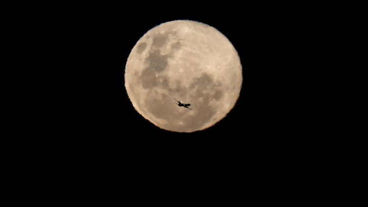 An aircraft passes in front of the last supermoon of 2025, known as the Cold Moon, in Cape Town, South Africa, December 4, 2025. REUTERS/Esa Alexander