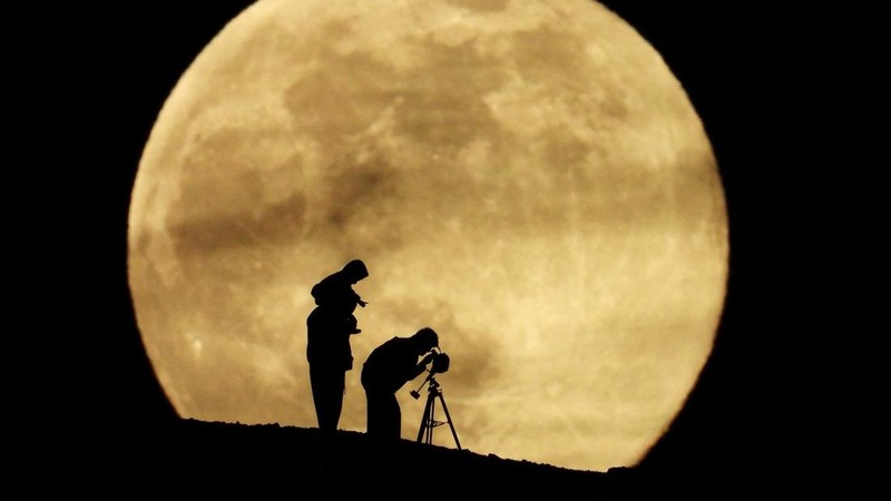 A couple and their daughter use a telescope to observe the last supermoon of 2025, known as the Cold Moon, in Aguimes, on the island of Gran Canaria, Spain, December 4, 2025. REUTERS/Borja Suarez     TPX IMAGES OF THE DAY