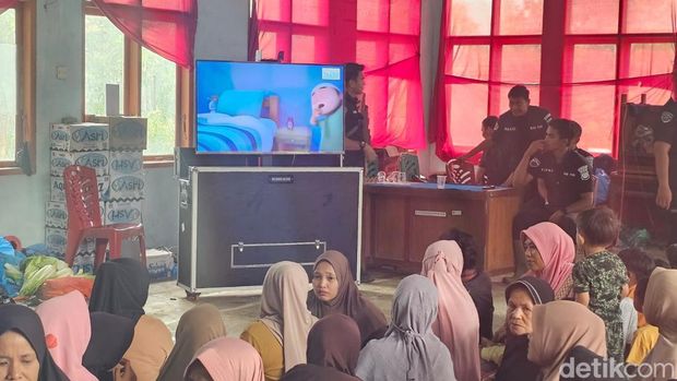 Warga terisolir di Jorong Koto Silungkang, Agam, menonton kartun dari layar monitor yang dibawa Polda Riau, Jumat (5/12/2025).