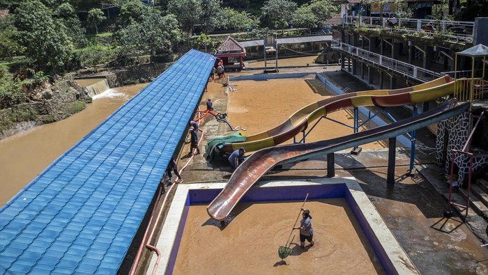 Warga membersihkan material lumpur pascabanjir di objek wisata Lembah Curugan Gunung Putri, Desa Mukapayung, Cililin, Kabupaten Bandung Barat, Jawa Barat, Jumat (5/12/2025). Bencana banjir yang terjadi pada Kamis (4/12) akibat meluapnya Sungai Cibitung tersebut menyebabkan sedikitnya lima hektar lahan persawahan rusak dan merendam objek wisata Lembah Curugan Gunung Putri serta kolam ikan milik BUMDes di kawasan itu. ANTARA FOTO/Abdan Syakura/bar