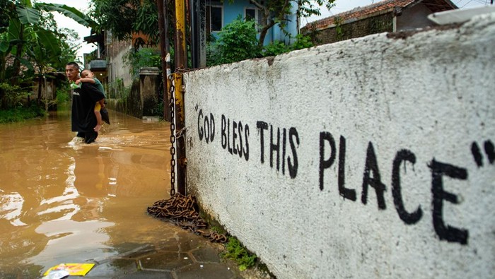 Warga membawa bayinya menggunakan ember saat melintasi banjir di Jalan Raya Dayeuhkolot, Kabupaten Bandung, Jawa Barat, Sabtu (6/12/2025). Banjir yang terjadi di Kabupaten Bandung meluas hingga berdampak ke 14 kecamatan dengan volume air yang mengalami kenaikan 10cm hingga 50cm sehingga membuat Pemerintah Kabupaten Bandung menetapkan status tanggap darurat bencana banjir serta longsor dari 6 Desember hingga 19 Desember mendatang. ANTARA FOTO/Novrian Arbi/foc.