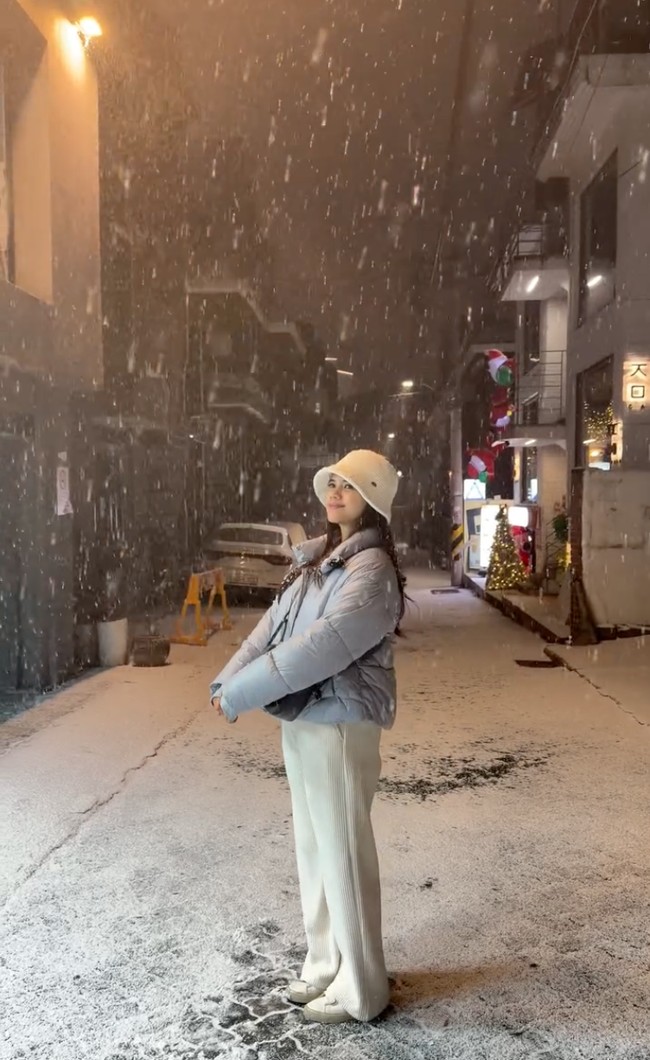 Audi tampak asik menikmati salju yang sedang turun di Seoul. Terlihat ia memadukan jaket tebal warna abu-abu dengan celana panjang putih dan bucket hat senada. Foto: Instagram/@audimarissa