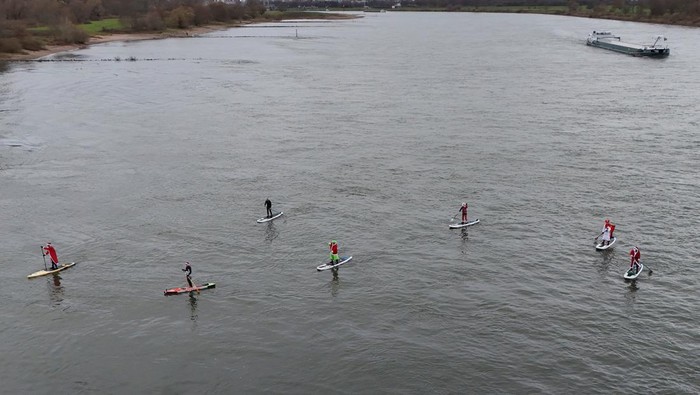 A drone view shows members of the Watersports Club Monheim dressed as Santa Claus, traditional St. Nicholas and the Grinch ride stand-up paddle boards (SUP) on the Rhine river in Monheim, Germany, December 6, 2025. REUTERS/Stephane Nitschke