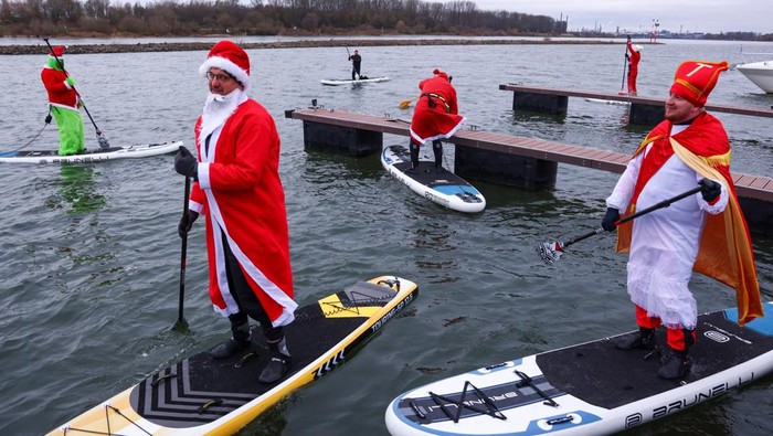 Members of the Watersports Club Monheim dressed as Santa Claus, traditional St. Nicholas and the Grinch start a tour on stand-up paddle boards (SUP) on the Rhine river in Leverkusen, Germany, December 6, 2025. REUTERS/Thilo Schmuelgen