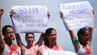 Para demonstran membawa poster yang bertuliskan 83.114 perempuan diperkosa di Brasil pada tahun 2024 (kiri), dan bertuliskan Adrielle Messias. 17 Tahun. Dibunuh dengan 5 tembakan oleh mantannya (kanan). REUTERS/Tita Barros