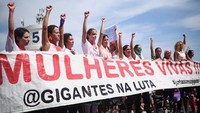 Sejumlah orang dengan membentangkan spanduk prote turun ke jalan di Rio de Janeiro untuk memprotes meningkatnya kasus femisida dan kekerasan berbasis gender yang terus terjadi di Brasil, pada hari Minggu (7/12/2025). REUTERS/Marina Calderon