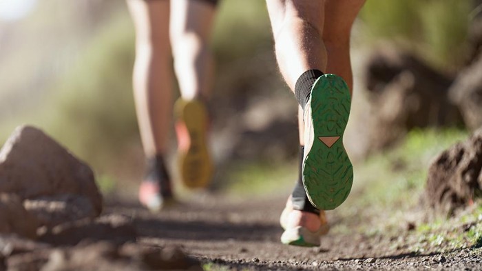 Healthy young couple running on mountain trail in morning. Trail running marathon fitness feet on rock fitness and healthy lifestyle