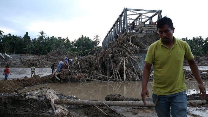 Warga melewati tumpukan puing kayu untuk menyeberangi Sungai Peusangan pascaputusnya jembatan Awe Geutah di Peusangan Siblah Krueng, Bireuen, Aceh, Minggu (7/12/2025). Kementerian Pekerjaan Umum dibantu TNI/Polri dan masyarakat terus memacu pembangunan jembatan bailey Awe Geutah yang menjadi salah satu jalan alternatif menuju Aceh Utara pascaputusnya jembatan Kuta Blang akibat banjir bandang di lintas jalan nasional Banda Aceh-Medan. ANTARA FOTO/Irwansyah Putra