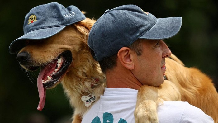 A man holds a Golden Retriever wearing a cap during a meetup seeking to break the world record for the largest gathering of the breed, in Buenos Aires, Argentina December 8, 2025. REUTERS/Agustin Marcarian TPX IMAGES OF THE DAY