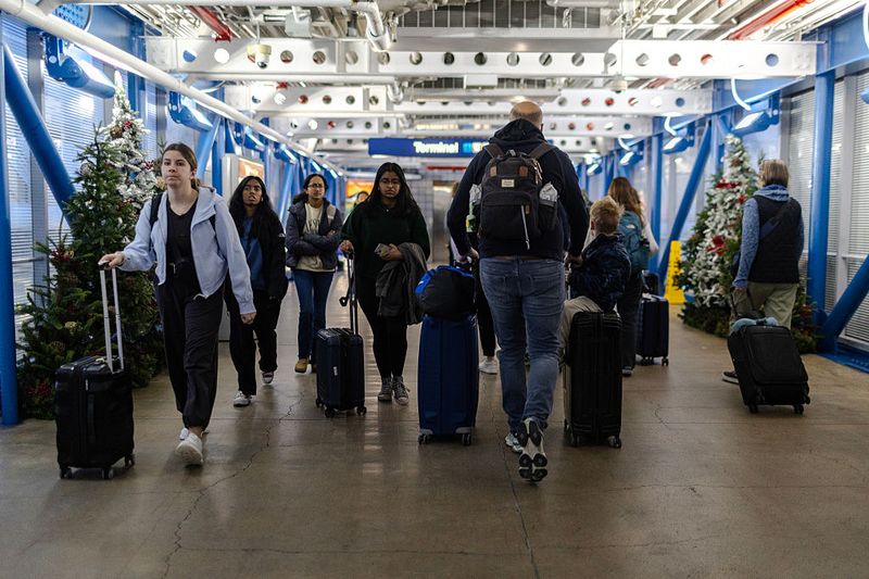 Fenomena Penumpang Pesawat Pakai Piama di Bandara AS CHICAGO, ILLINOIS - NOVEMBER 30: Travelers cross a pedestrian bridge at O'Hare International airport on November 30, 2025 in Chicago, Illinois. The Federal Aviation Administration is gearing up for the busy Thanksgiving travel time and is ready to get more than 360,000 flights to their destinations. (Photo by Jim Vondruska/Getty Images)