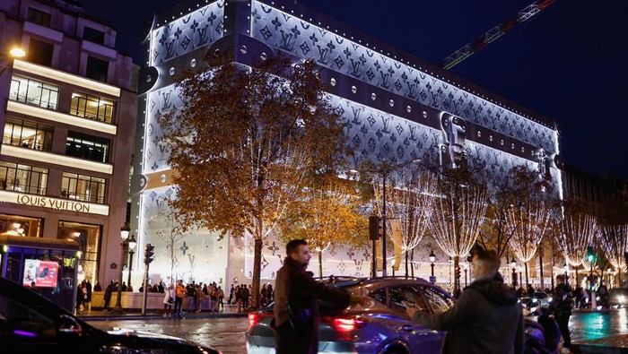 People and vehicles move past the Louis Vuitton store lit up with Christmas illuminations on the Champs-Elysees avenue in Paris, France, December 7, 2025. REUTERS/Benoit Tessier