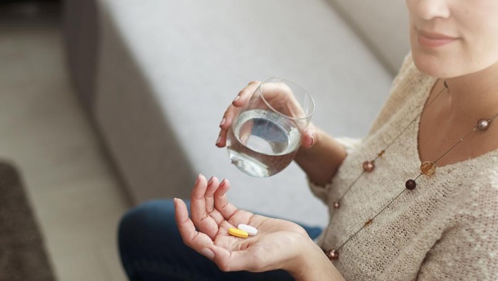 Ilustrasi wanita minum suplemen atau vitamin