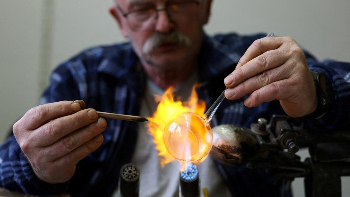 A worker heats glass before blowing a glass bauble at Silverado, a manufacturer of hand-blown Christmas ornaments, in Jozefow, outside Warsaw, Poland, December 2, 2025. REUTERS/Kacper Pempel