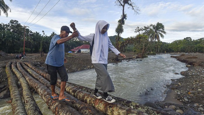 Pelajar penyintas bencana banjir bandang melewati jalan berbatu di Jorong Kayu Pasak Selatan, Nagari Salareh Aia, Palembayan, Agam, Sumatera Barat, Selasa (9/12/2025). Sekitar 50 siswa SMA di jorong tersebut mulai melaksananakan ujian sekolah pada hari ini walaupun harus menyeberangi sungai dan melewati jalan terdampak banjir bandang, sementara puluhan siswa SD dan SMP sederajat masih diliburkan. ANTARA FOTO/Wahdi Septiawan