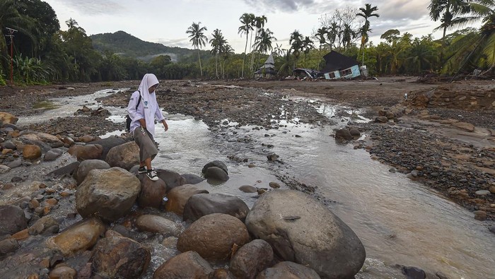 Pelajar penyintas bencana banjir bandang melewati jalan berbatu di Jorong Kayu Pasak Selatan, Nagari Salareh Aia, Palembayan, Agam, Sumatera Barat, Selasa (9/12/2025). Sekitar 50 siswa SMA di jorong tersebut mulai melaksananakan ujian sekolah pada hari ini walaupun harus menyeberangi sungai dan melewati jalan terdampak banjir bandang, sementara puluhan siswa SD dan SMP sederajat masih diliburkan. ANTARA FOTO/Wahdi Septiawan