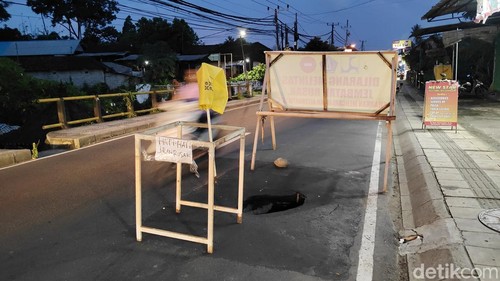 Lubang di Jalan Raya Lukluk-Darmasaba, Kecamatan Abiansemal diberi plang peringatan, Selasa (9/12/2025).