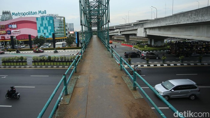 Warga menyeberang jalan Ahmad Yani, Bekasi, Selasa (9/12/2025). Jembatan Penyeberangan Orang (JPO) di jalan Ahmad Yani, Bekasi viral tanpa pengaman. Besi-besi yang harusnya jadi pengaman hilang.