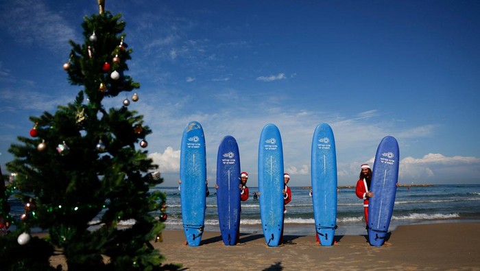 Surfers dressed as Santa Claus carry their boards as they enter the Mediterranean Sea, in Tel Aviv, Israel December 2, 2025. REUTERS/Ammar Awad     TPX IMAGES OF THE DAY