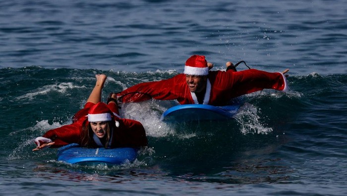 Surfers dressed as Santa Claus carry their boards as they enter the Mediterranean Sea, in Tel Aviv, Israel December 2, 2025. REUTERS/Ammar Awad TPX IMAGES OF THE DAY