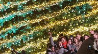 Warga berfoto di alun-alun umum dengan latar pohon Natal, menikmati sejenak ketenangan sebelum sirene udara kembali meraung. REUTERS/Gleb Garanich