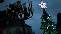 Termometer apotek menunjukkan suhu 15 derajat Celcius di dekat komidi putar pohon Natal di Alun-alun Graslin, Nantes, Rabu (9/12/2025) waktu setempat. Cuaca sejuk tak menyurutkan semangat warga menikmati suasana liburan. REUTERS/Stephane Mahe