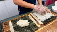 Essel menggunakan jenis beras khusus agar bisa menempel sempurna ke lembaran rumput laut. Perlu ketelatenan pegawai untuk menyebarkan nasi ke seluruh permukaan rumput laut agar merata dan mudah digulung bersama isian lain nantinya. Foto: Andi Annisa DR/detikfood