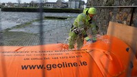 Pekerja memasang penghalang banjir di pusat Kota Galway, Irlandia, saat peringatan angin Status Oranye dikeluarkan jelang datangnya Badai Bram, Selasa (9/12/2025) waktu setempat. REUTERS/Clodagh Kilcoyne