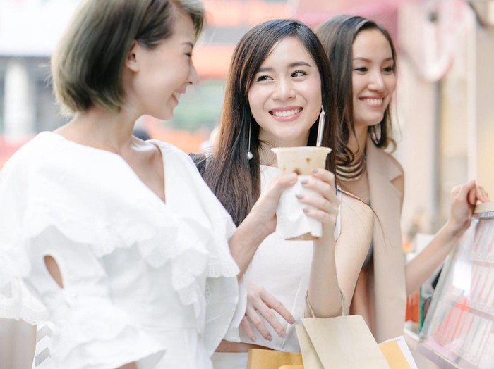 Young beautiful women shopping together, outdoors, smiling, buying refreshing drink