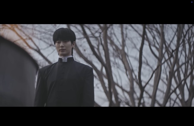 Byeon Woo Seok terungkap menjadi salah satu aktor yang terlibat dalam project ini, menampilkan pesonanya sebagai pastor. Adegan di awal video menyorotnya saat membakar kaset-kaset misterius, tangannya juga ditarik seorang bocah. Foto: dok. YouTube @DolphinersOfficial