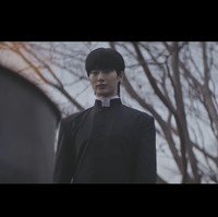 Byeon Woo Seok terungkap menjadi salah satu aktor yang terlibat dalam project ini, menampilkan pesonanya sebagai pastor. Adegan di awal video menyorotnya saat membakar kaset-kaset misterius, tangannya juga ditarik seorang bocah. Foto: dok. YouTube @DolphinersOfficial